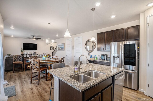 kitchen with dark brown cabinetry, a ceiling fan, appliances with stainless steel finishes, light wood-type flooring, and a sink