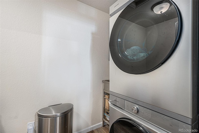 laundry area featuring laundry area, stacked washer and dryer, and wood finished floors