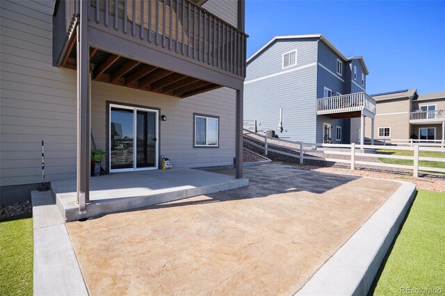 back of property featuring fence, a patio, and a balcony