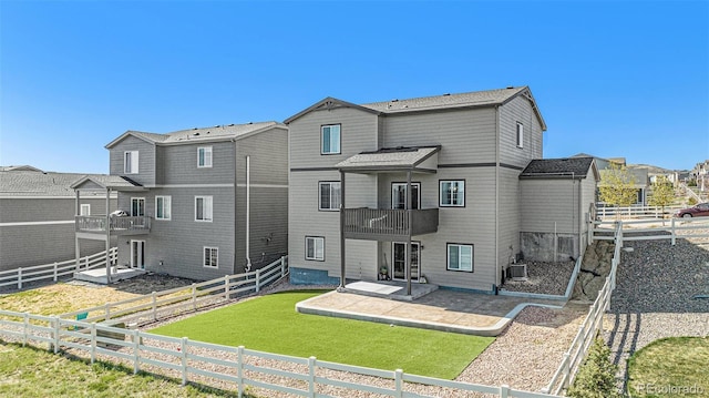 back of property with a balcony, a patio, a fenced backyard, a lawn, and a residential view