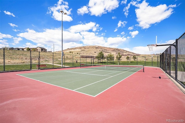 view of tennis court featuring a mountain view, community basketball court, and fence