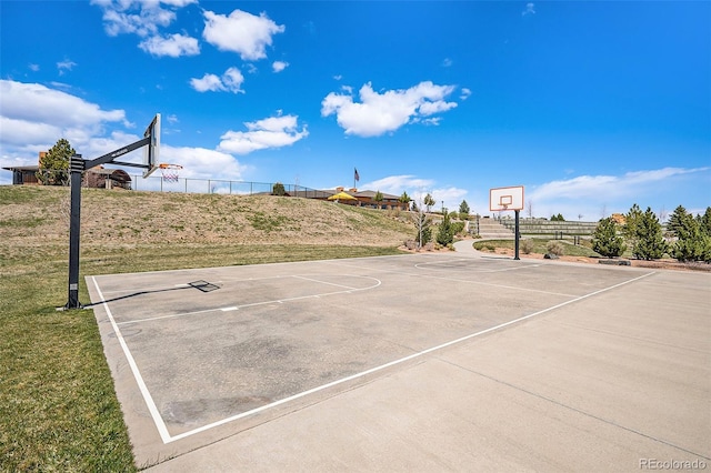 view of basketball court with fence, community basketball court, and a lawn