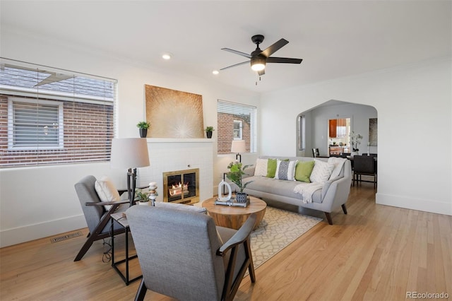 living room featuring ornamental molding, a brick fireplace, ceiling fan, and light wood-type flooring