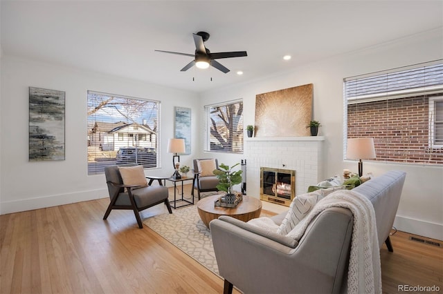 living room featuring wood-type flooring, ornamental molding, and a fireplace