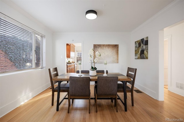 dining room with crown molding, plenty of natural light, and light hardwood / wood-style floors