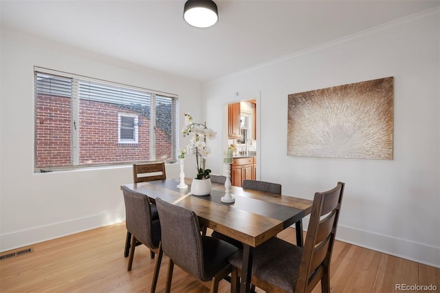 dining area featuring crown molding, sink, and light hardwood / wood-style floors