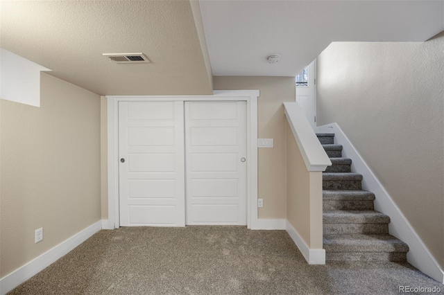 staircase with carpet floors and a textured ceiling