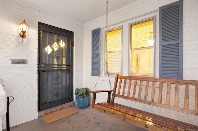 doorway to property featuring covered porch and brick siding