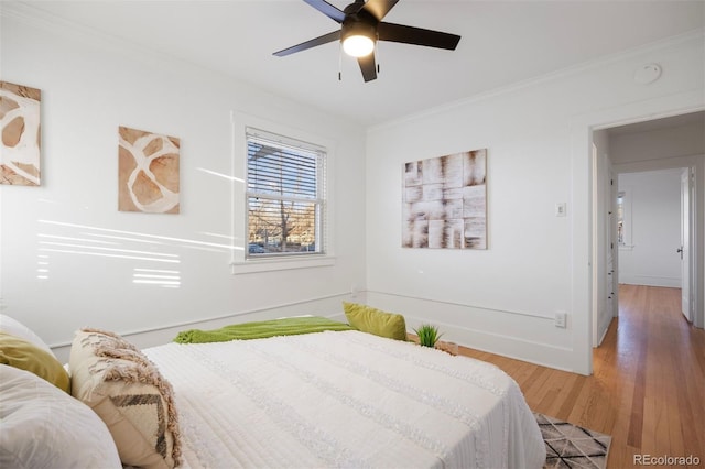 bedroom with baseboards, a ceiling fan, light wood-style flooring, and crown molding