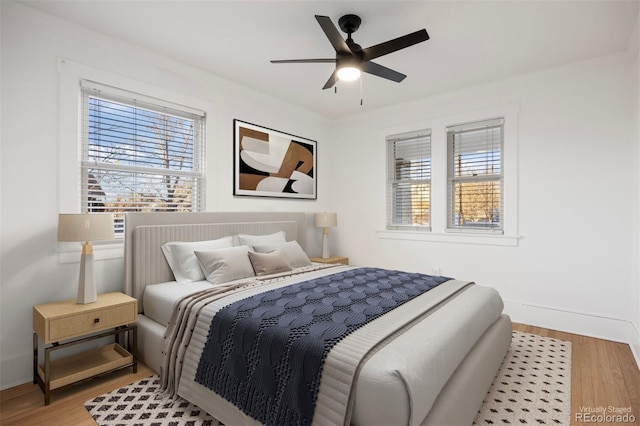 bedroom featuring baseboards, wood finished floors, and a ceiling fan