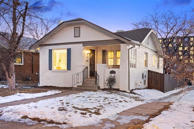 bungalow-style house with brick siding, a chimney, and fence