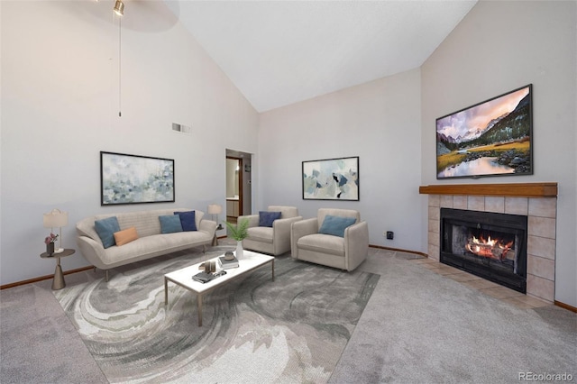 carpeted living room with a tile fireplace, ceiling fan, and high vaulted ceiling