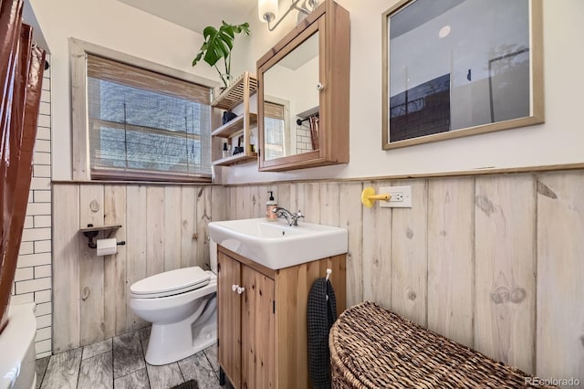 2844 Bellaire St, Denver, CO 80207 - bathroom featuring wainscoting, vanity, toilet, wooden walls, and a shower with shower curtain