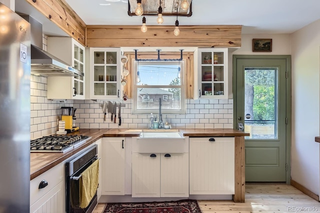 2844 Bellaire St, Denver, CO 80207 - kitchen with stainless steel appliances, wooden counters, decorative backsplash, white cabinets, and light wood-type flooring