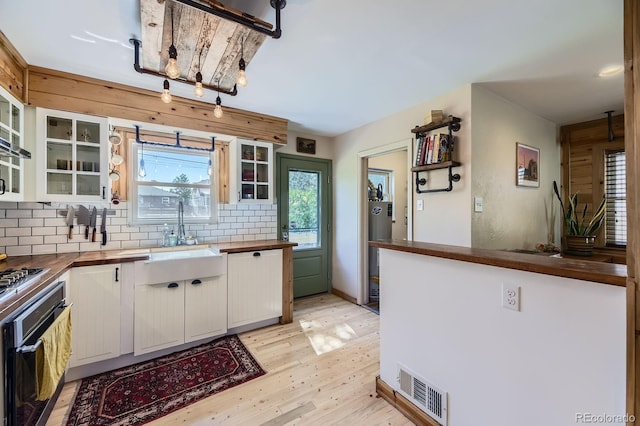 2844 Bellaire St, Denver, CO 80207 - kitchen with appliances with stainless steel finishes, a sink, decorative backsplash, light wood-style floors, and white cabinetry