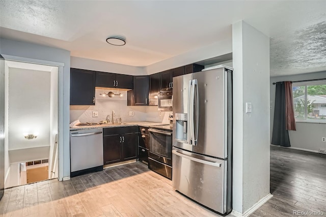 5274 Alkire St, Arvada, CO 80002 - kitchen featuring appliances with stainless steel finishes, hardwood / wood-style flooring, light countertops, a textured ceiling, and decorative backsplash