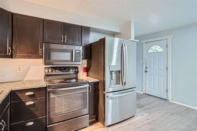 5274 Alkire St, Arvada, CO 80002 - kitchen featuring appliances with stainless steel finishes, light wood-style flooring, dark brown cabinets, and light stone counters