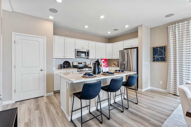 23782 E 33rd Pl, Aurora, CO 80019 - kitchen featuring appliances with stainless steel finishes, light wood-style floors, white cabinets, light countertops, and decorative backsplash