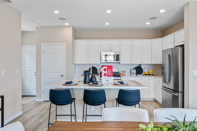 23782 E 33rd Pl, Aurora, CO 80019 - kitchen with stainless steel appliances, light countertops, white cabinetry, a kitchen island, and a kitchen breakfast bar