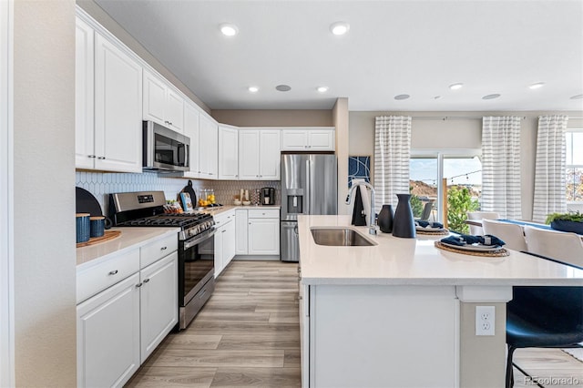 23782 E 33rd Pl, Aurora, CO 80019 - kitchen featuring appliances with stainless steel finishes, a sink, an island with sink, white cabinets, and backsplash