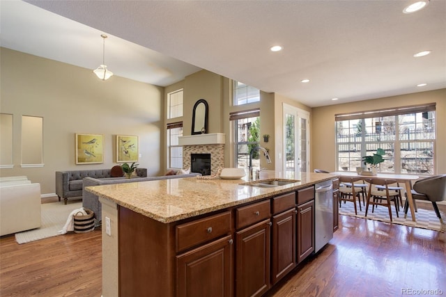 kitchen featuring a fireplace, a wealth of natural light, dark wood-type flooring, dishwasher, and a sink