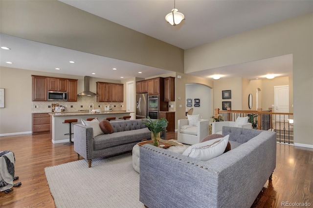living area featuring baseboards, recessed lighting, arched walkways, and wood finished floors