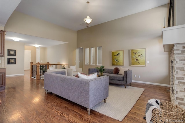living room with a fireplace, a high ceiling, baseboards, and wood finished floors
