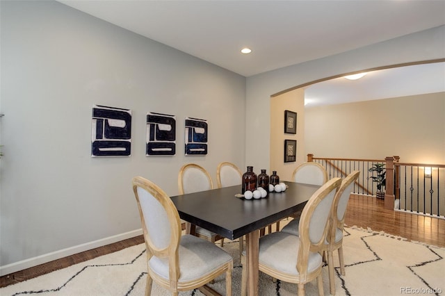 dining room with recessed lighting, arched walkways, light wood-style floors, and baseboards