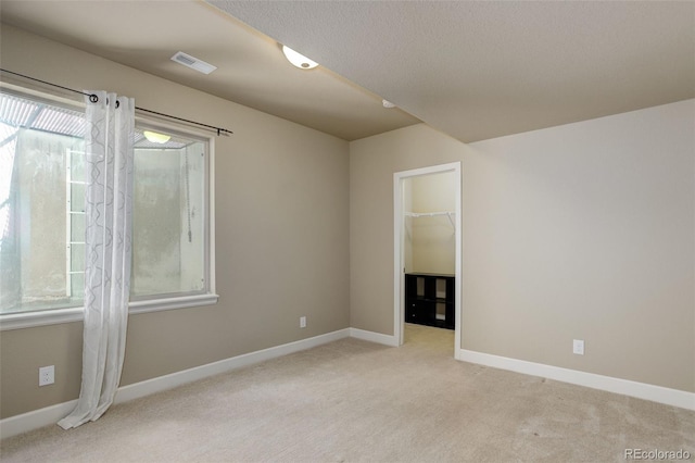 unfurnished room featuring visible vents, baseboards, light carpet, and a textured ceiling