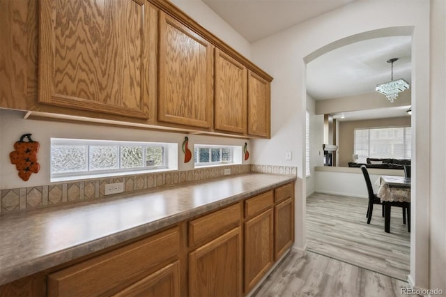 5293 Malaya St, Denver, CO 80249 - kitchen featuring brown cabinetry, arched walkways, a notable chandelier, and light wood finished floors