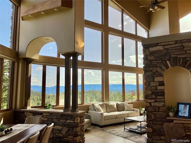 living room featuring a high ceiling, a water and mountain view, decorative columns, and ceiling fan