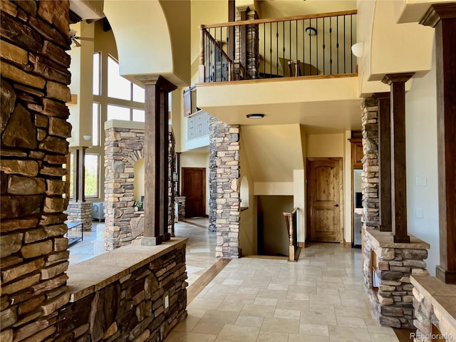 entryway with ornate columns, a high ceiling, and tile floors