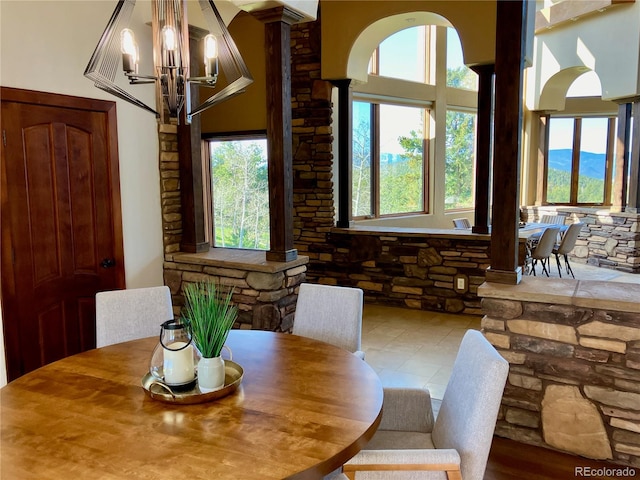 dining room featuring ornate columns, a chandelier, and a mountain view