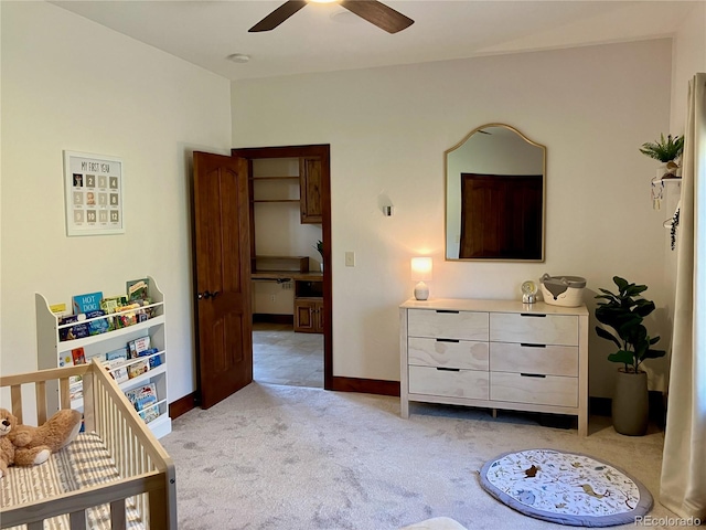 carpeted bedroom with a nursery area and ceiling fan