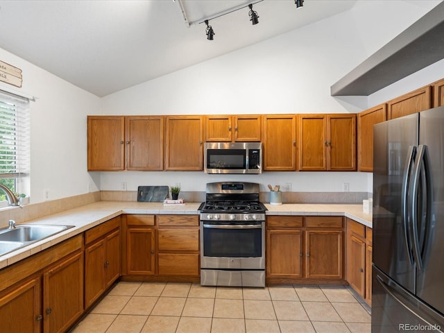 4436 Windmill Dr, Brighton, CO 80601 - kitchen featuring stainless steel appliances, vaulted ceiling, brown cabinetry, light tile patterned floors, and rail lighting