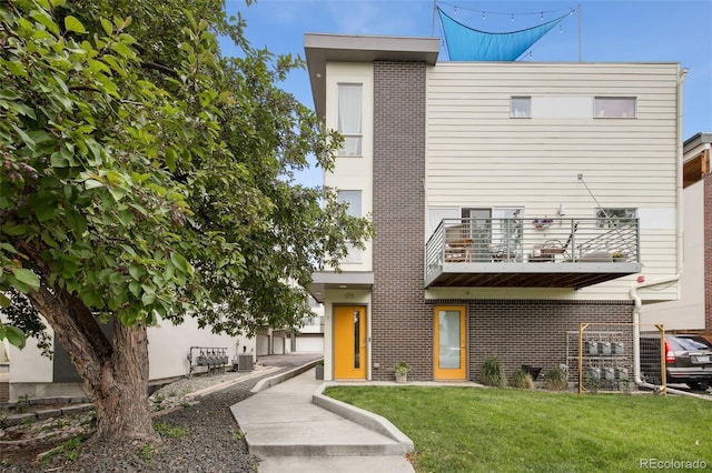 1711 Hooker St Unit 2, Denver, CO 80204 - view of front of house featuring brick siding, a balcony, and a front yard