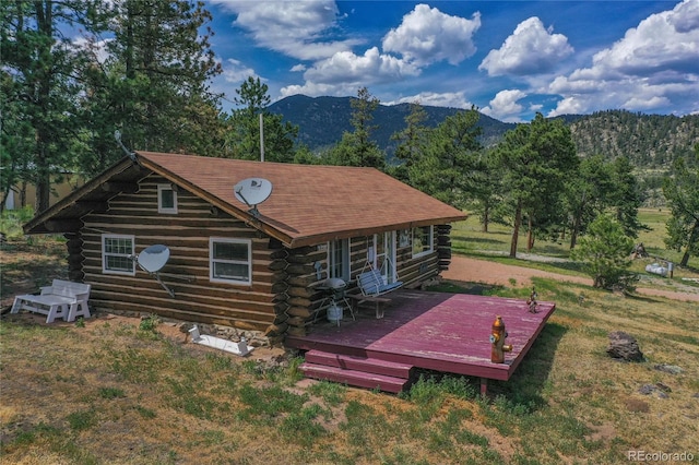 back of house with a yard and a deck with mountain view