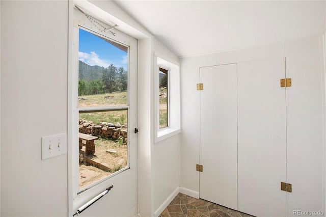 entryway featuring dark tile flooring and vaulted ceiling