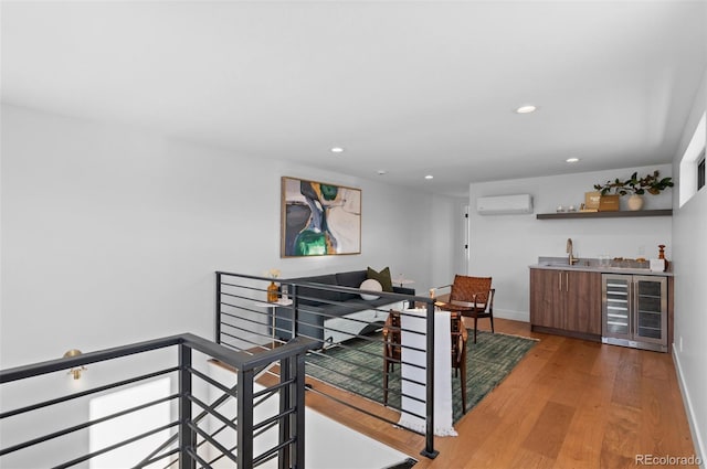 interior space featuring an AC wall unit, wet bar, beverage cooler, and light hardwood / wood-style floors