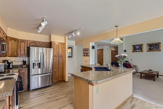kitchen featuring hanging light fixtures, a sink, brown cabinetry, stainless steel appliances, and backsplash