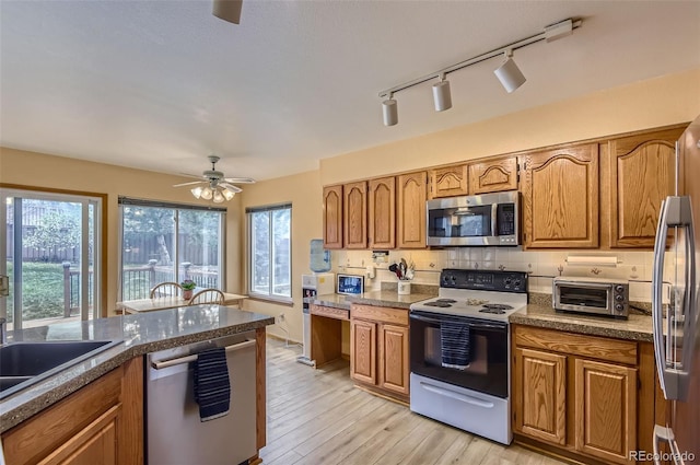 kitchen featuring appliances with stainless steel finishes, brown cabinetry, and a ceiling fan