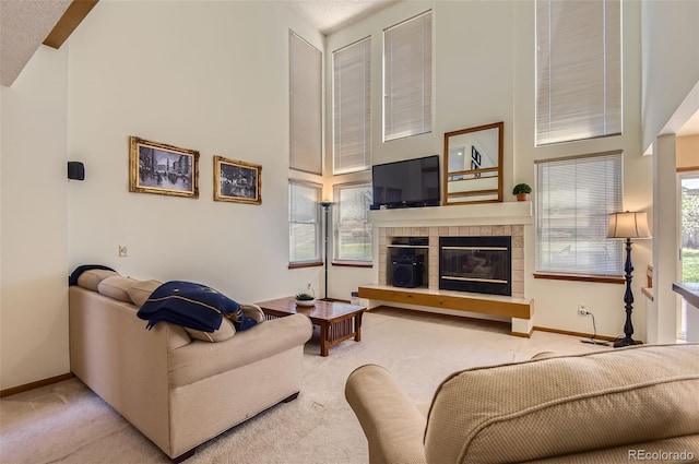living room with high vaulted ceiling, baseboards, carpet flooring, and a tile fireplace