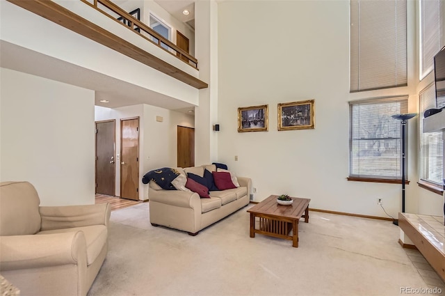 living area with baseboards, light carpet, and a towering ceiling
