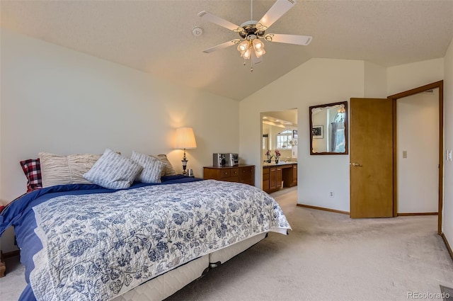 bedroom with ceiling fan, light colored carpet, baseboards, lofted ceiling, and ensuite bath