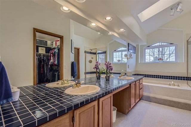 full bathroom featuring a garden tub, double vanity, a shower stall, a sink, and a skylight