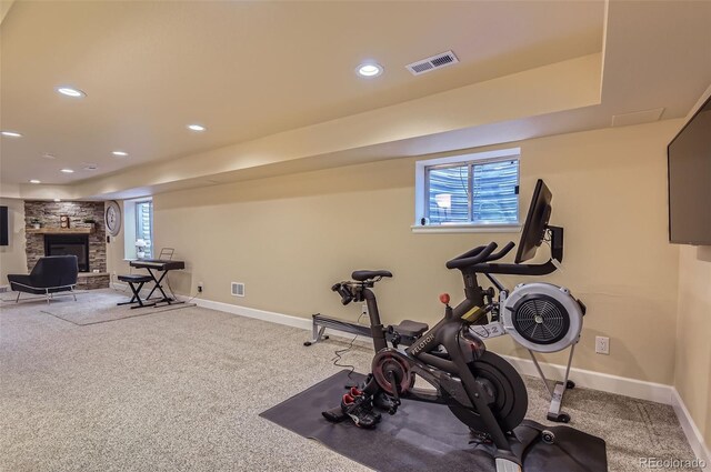 workout room with visible vents, baseboards, and a stone fireplace
