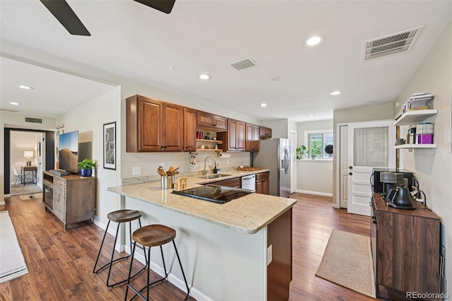 9150 Fir Dr, Thornton, CO 80229 - kitchen featuring stainless steel fridge, open shelves, a breakfast bar, light stone counters, and brown cabinetry