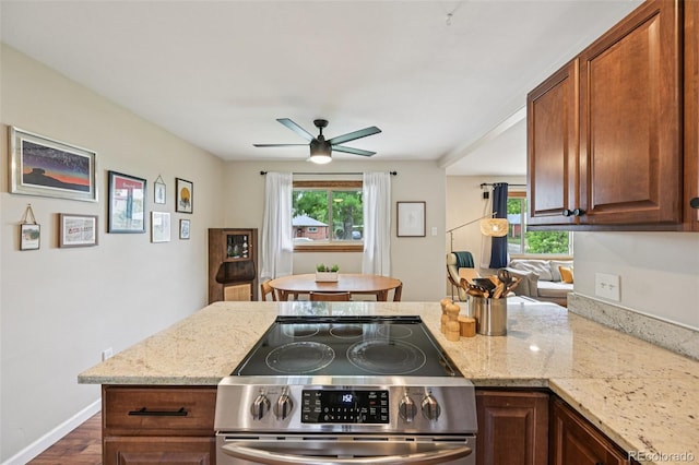 9150 Fir Dr, Thornton, CO 80229 - kitchen with stainless steel range with electric stovetop, ceiling fan, a peninsula, and light stone countertops
