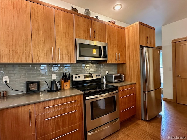 26 S Trailside Cir Unit A, Salida, CO 81201 - kitchen featuring appliances with stainless steel finishes, decorative backsplash, brown cabinetry, and light wood-style floors