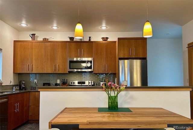 26 S Trailside Cir Unit A, Salida, CO 81201 - kitchen with stainless steel appliances, brown cabinetry, hanging light fixtures, tasteful backsplash, and dark countertops